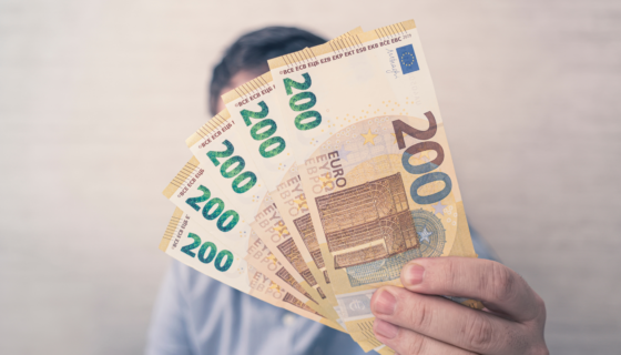 Ein Mann Hält Fünf 200-Euro-Banknoten In Der Hand Und Zeigt Diese In Die Kamera.