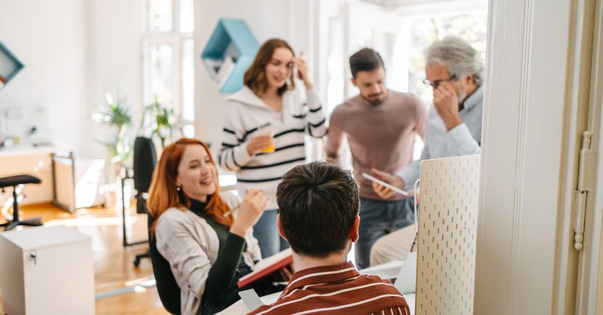 Eine Gruppe von Kollegen (3 Männer und 2 Frauen) unterhält sich im Büro